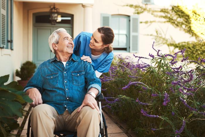 A carer pushing a man in a wheelchair