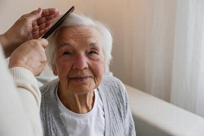 An elderly woman getting her hair combed